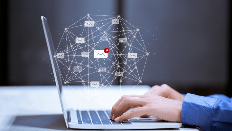 Hands typing on a laptop with digital email icons and network connections, representing online communication