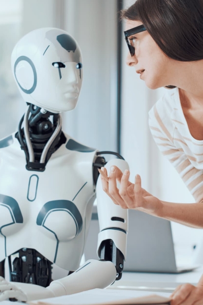 Woman collaborating with humanoid robot at computer, discussing artificial intelligence and robotics development