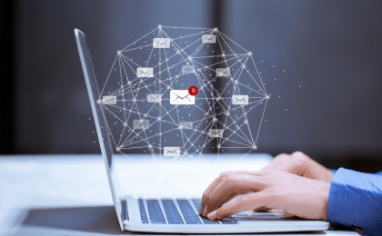 Hands typing on a laptop with digital email icons and network connections, representing online communication