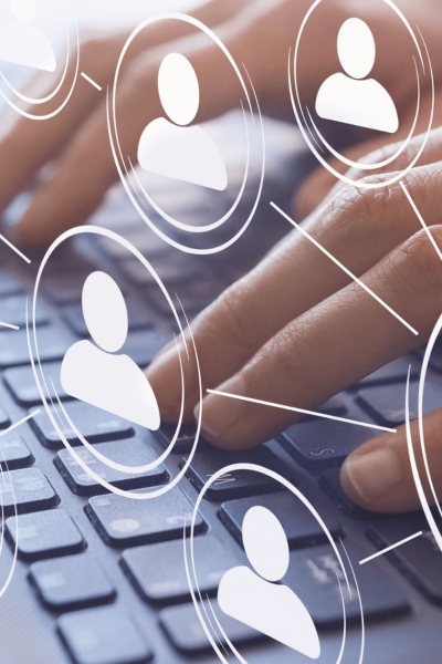 Hands typing on a computer keyboard with digital icons of emails and people, symbolizing email marketing and networking